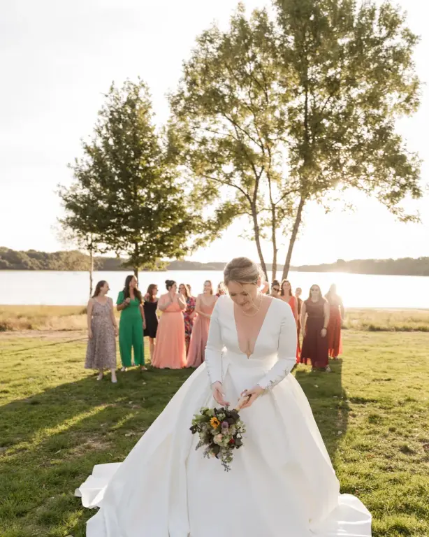 Mariée préparant son bouquet devant ses proches au bord d'un lac